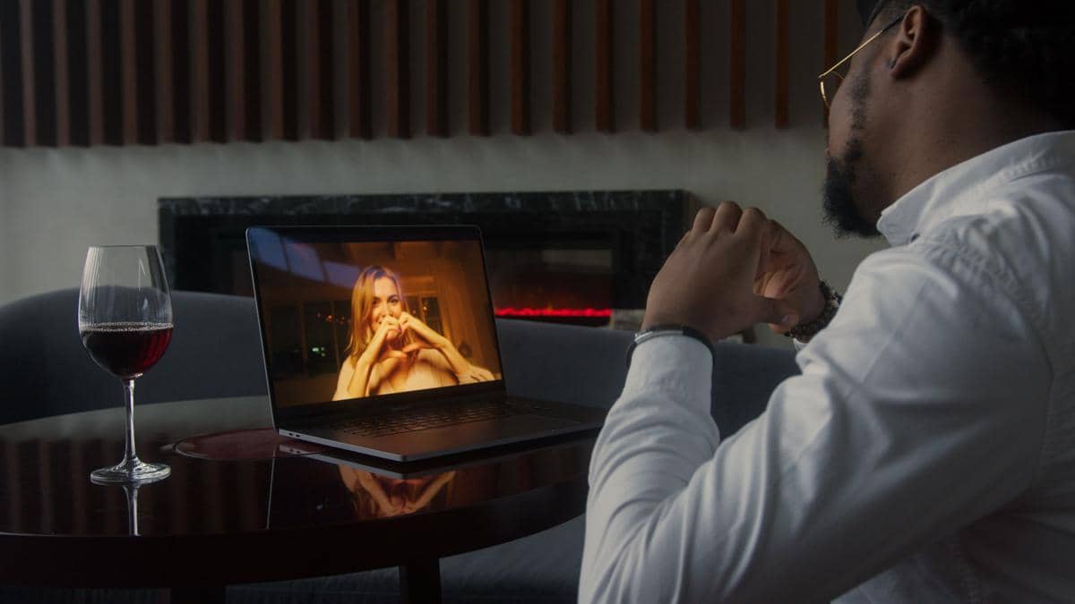 pria menatap layar laptop yang menampilkan perempuan tersenyum membentuk simbol hati