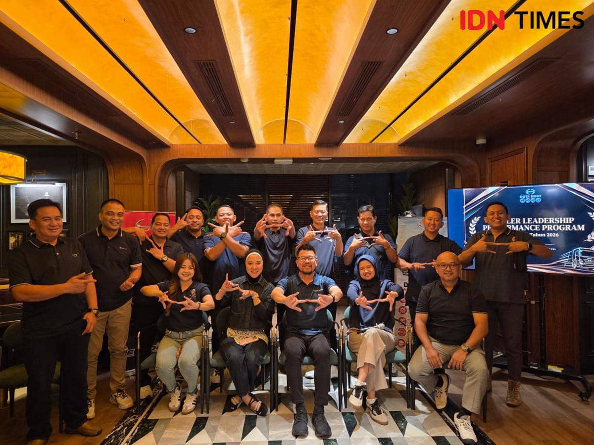 Sejumlah konsumen dan pimpinan Duta Hino berpose bersama sambil membentuk simbol jari logo Hino dalam acara.