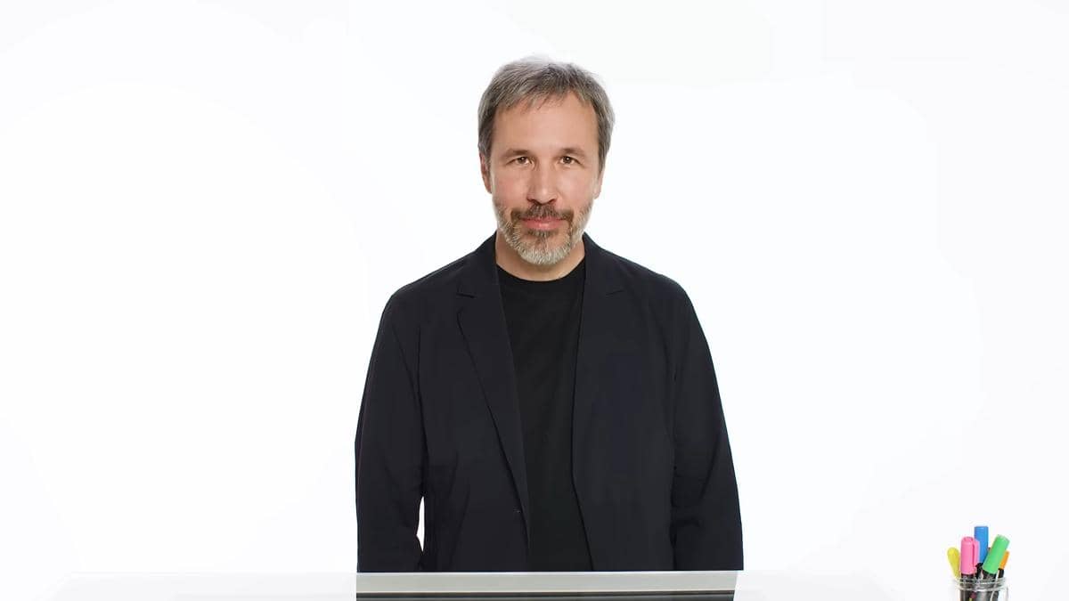Potret Denis Villeneuve dalam cuplikan video YouTube Vanity Fair dengan latar studio berwarna gelap di belakangnya.