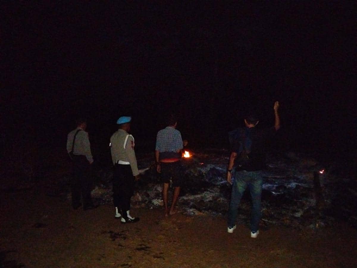 Petugas kepolisian melakukan olah TKP di area tiga rumah panggung yang hangus dibakar oleh sejumlah pria.