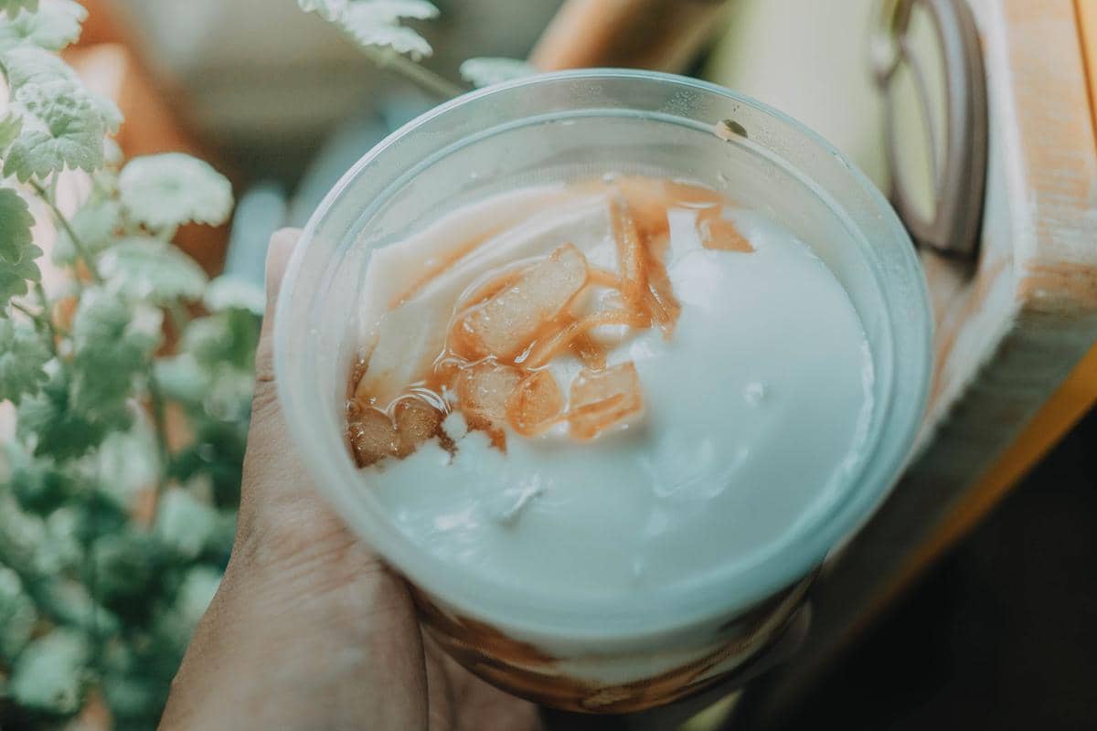 Semangkuk ginger milk pudding berwarna putih lembut disajikan sebagai hidangan penutup hangat dengan aroma jahe.