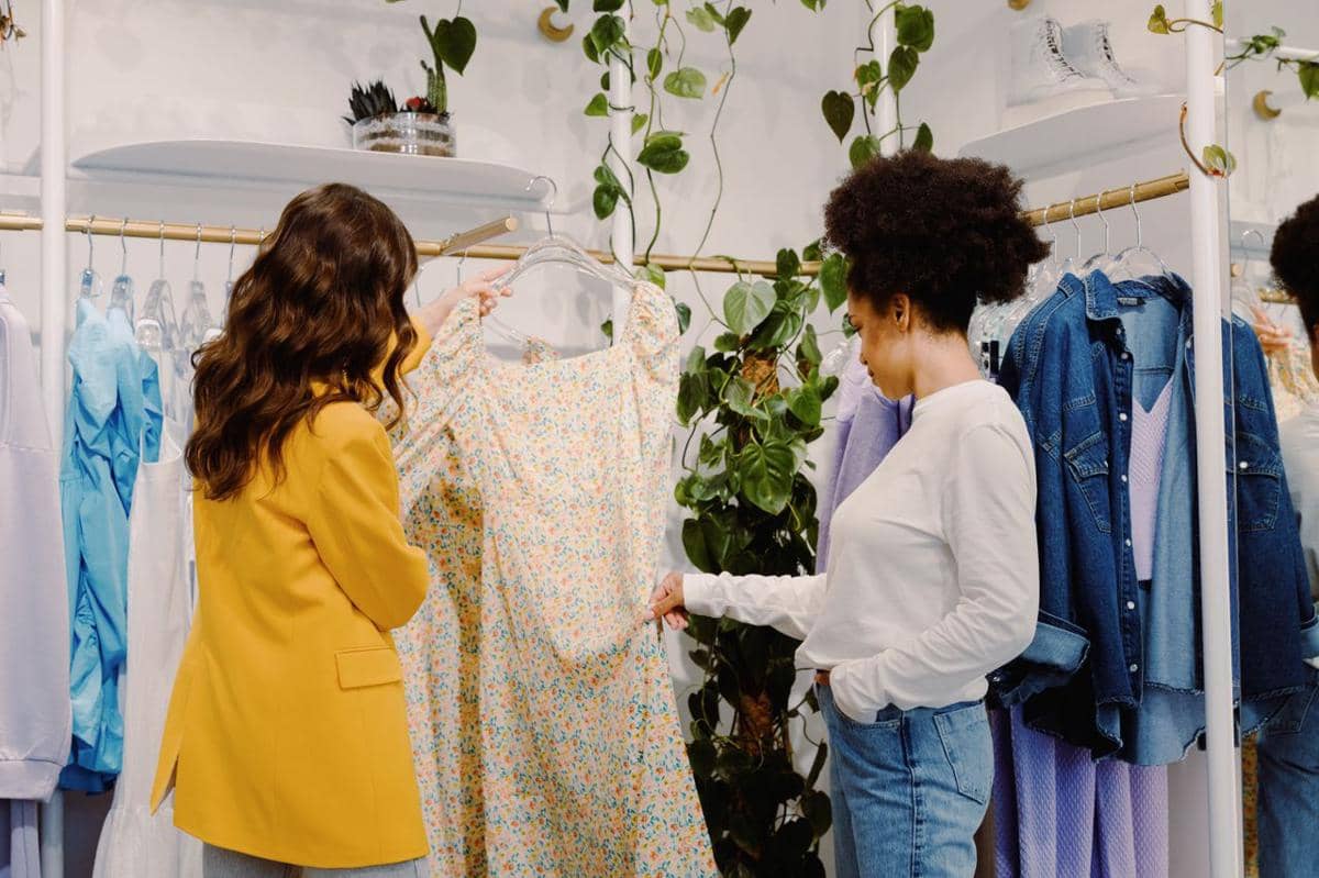 ilustrasi dua wanita sedang berbelanja pakaian bergaya di butik trendi