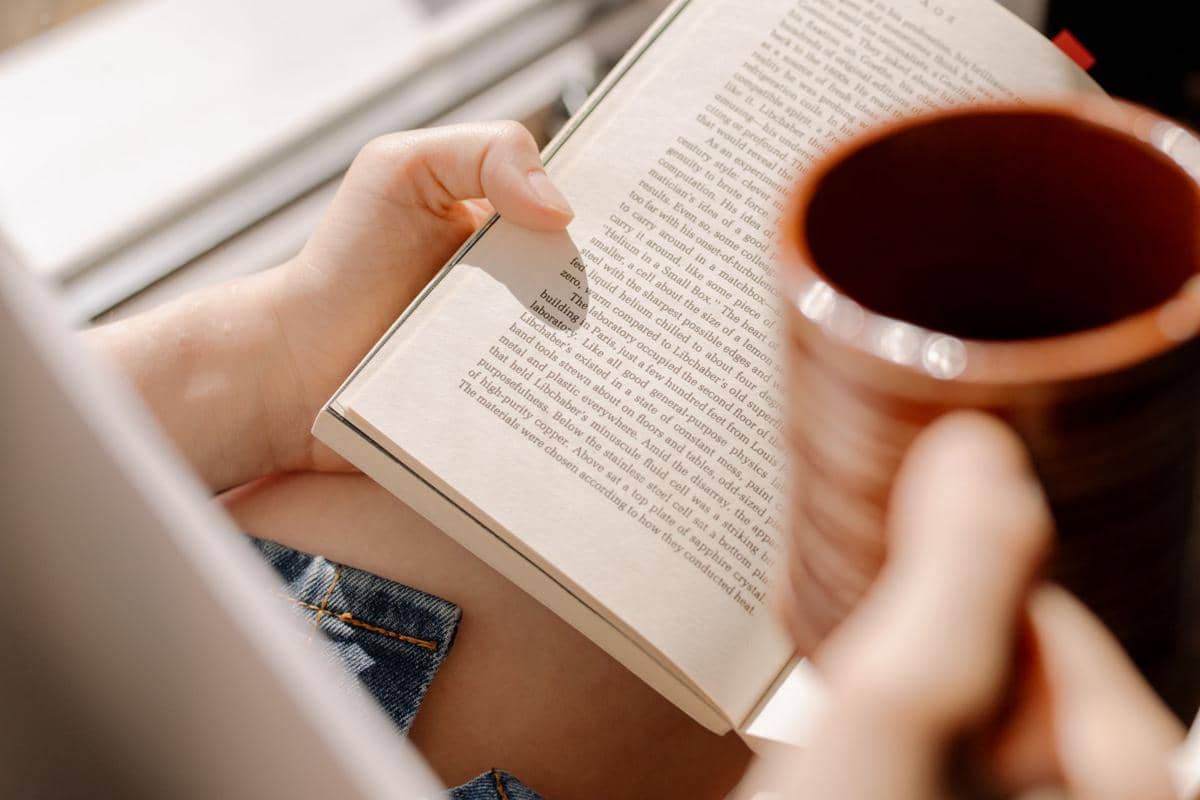 membaca buku sambil menikmati secangkir kopi
