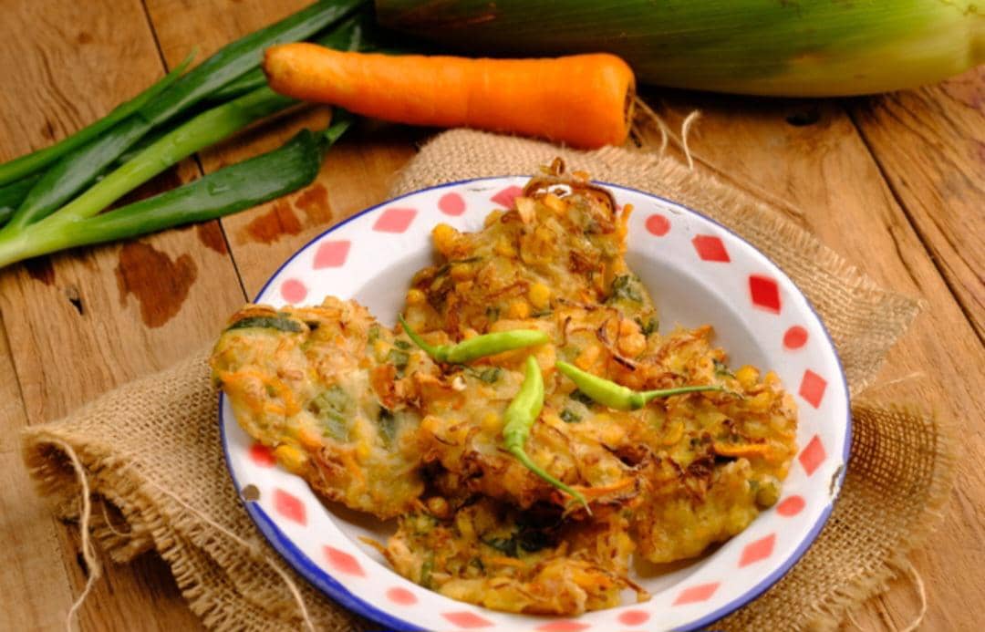 Sepiring bakwan sayur goreng berwarna keemasan disajikan sebagai camilan dalam potret hidangan oleh Ika Rakhmawati Hilal.