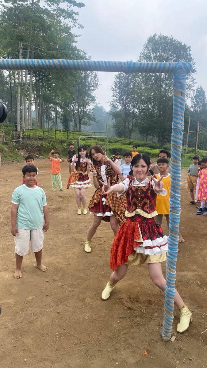 Seorang anggota JKT48 berpose di lokasi syuting video musik “Ayo Senyumlah” dalam momen di balik layar.