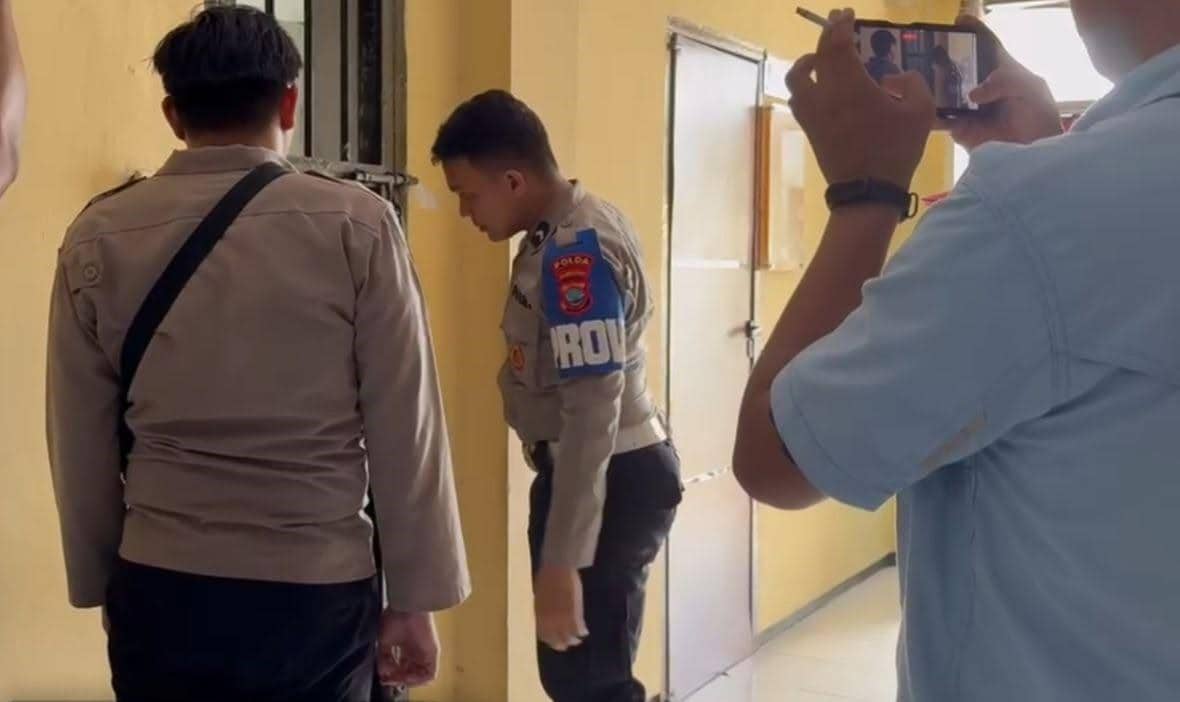 Seorang polisi mengawal anggota Polres Minsel yang ditahan di Polda Sulawesi Utara pada Senin, 26 Oktober 2026.