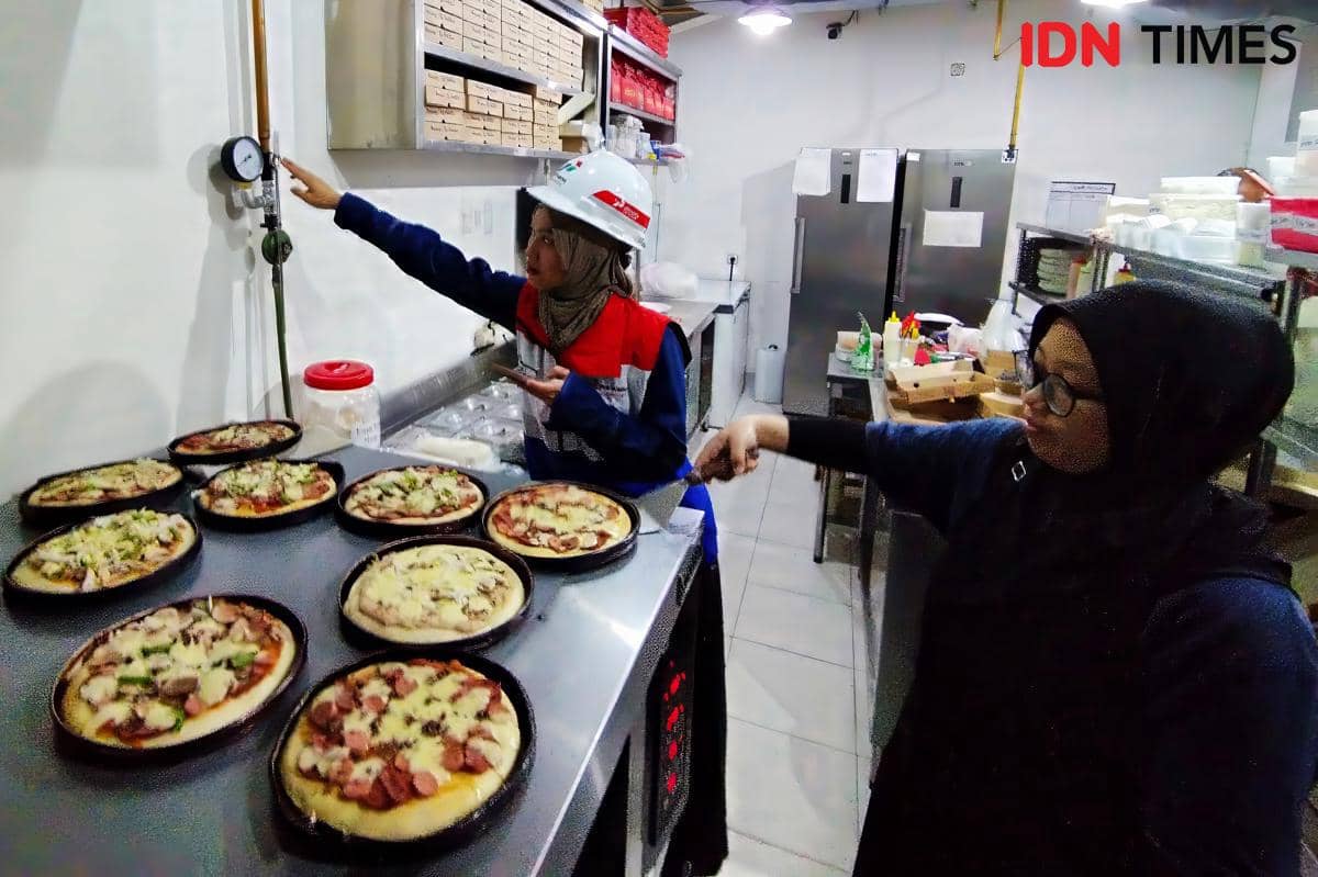 Petugas PGN (kiri) mengecek keandalan gas bumi di tengah aktivitas dapur Portobello di Jalan Halmahera Semarang. (IDN Times/Dhana Kencana)