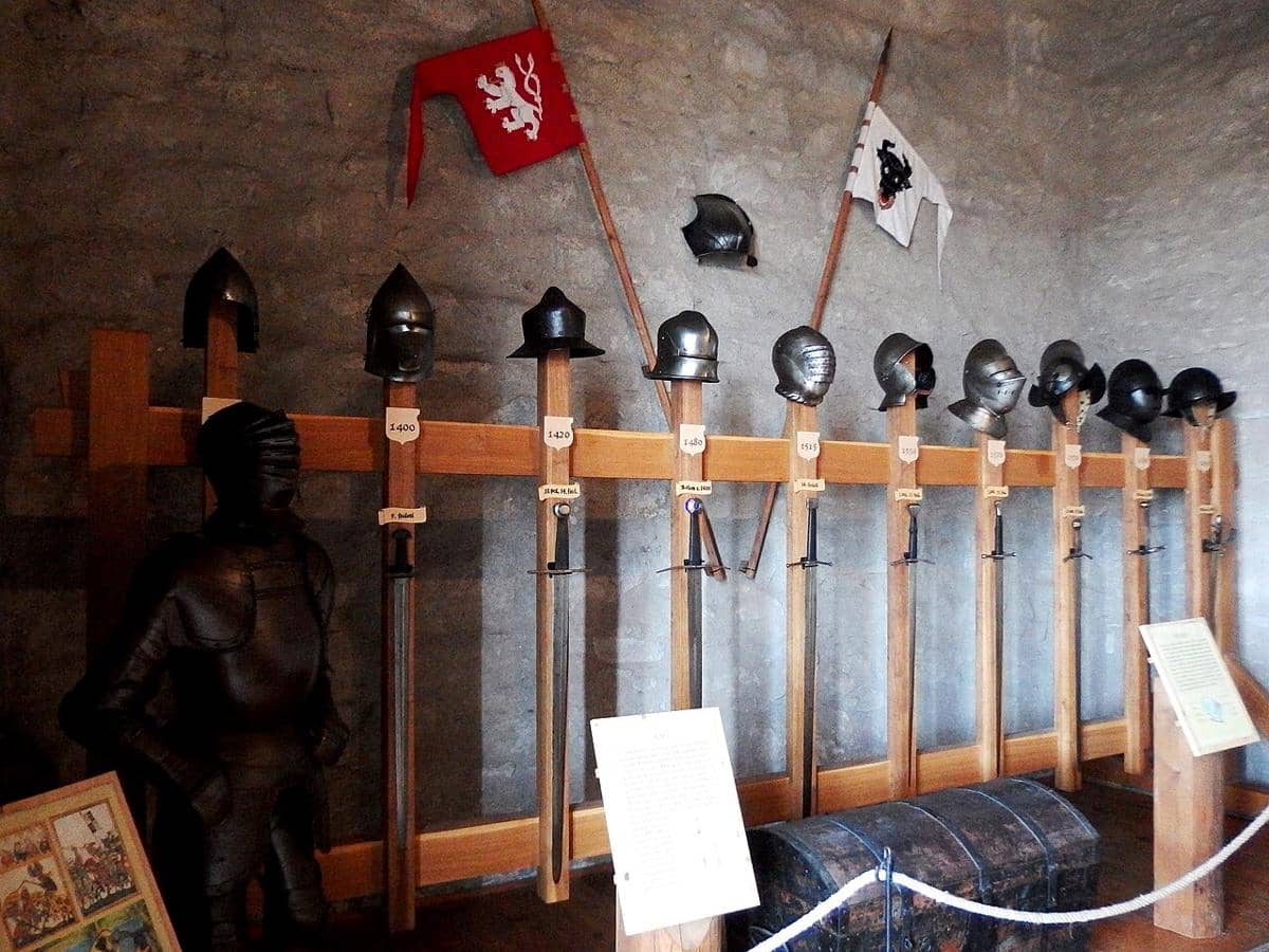 Tampilan baju besi, helm, dan pedang bersejarah di gudang senjata Kunětická hora Castle.